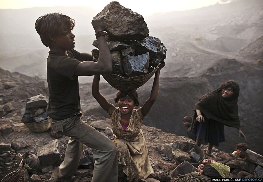 A young woman trips As She carries A large basket illegally mined coal